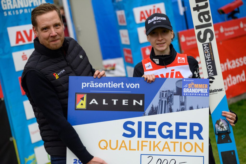 Nika Prevc hält in Klingenthal den Siegerscheck für den Gewinn der Qualifikation beim Sommer Grand Prix.